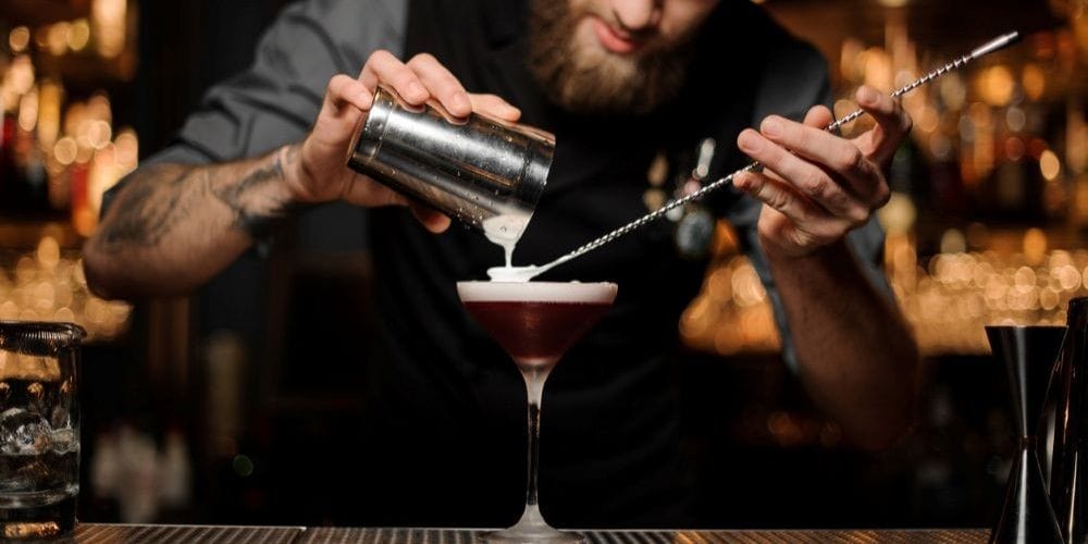Bartender creating a cocktail drink at the bar.