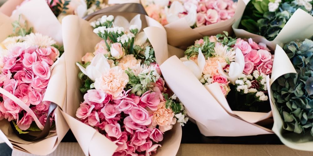 A lot of flower bouquets at the florist shop on the table made of hydrangea, roses, peonies, eustoma in pink and sea green colors.